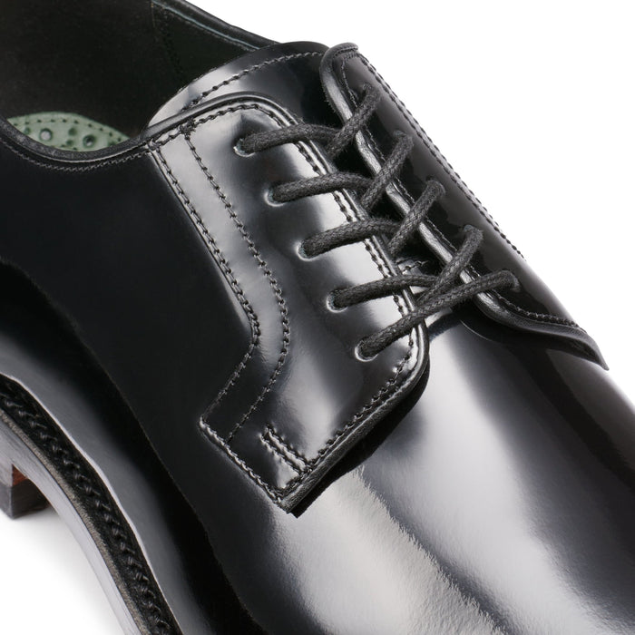 Close-up of black patent leather derby shoe laces and eyelets.