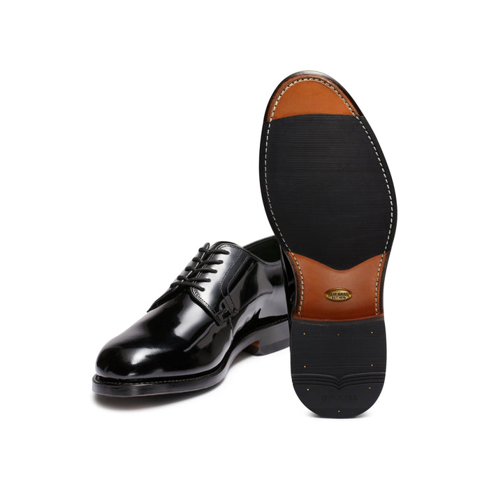 Black patent leather derby shoe paired with its tan leather sole, angled view.