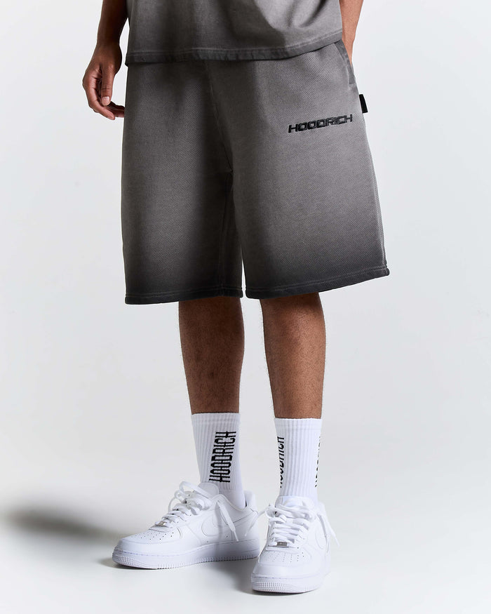 Model wearing oversized black oil wash shorts with Hoodrich logo embroidery, white socks, and white trainers.