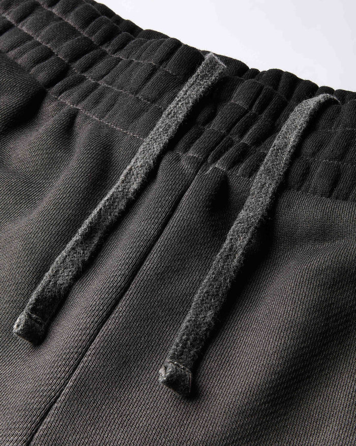 Close-up of the elasticated waistband and drawstring on the black oil wash shorts.