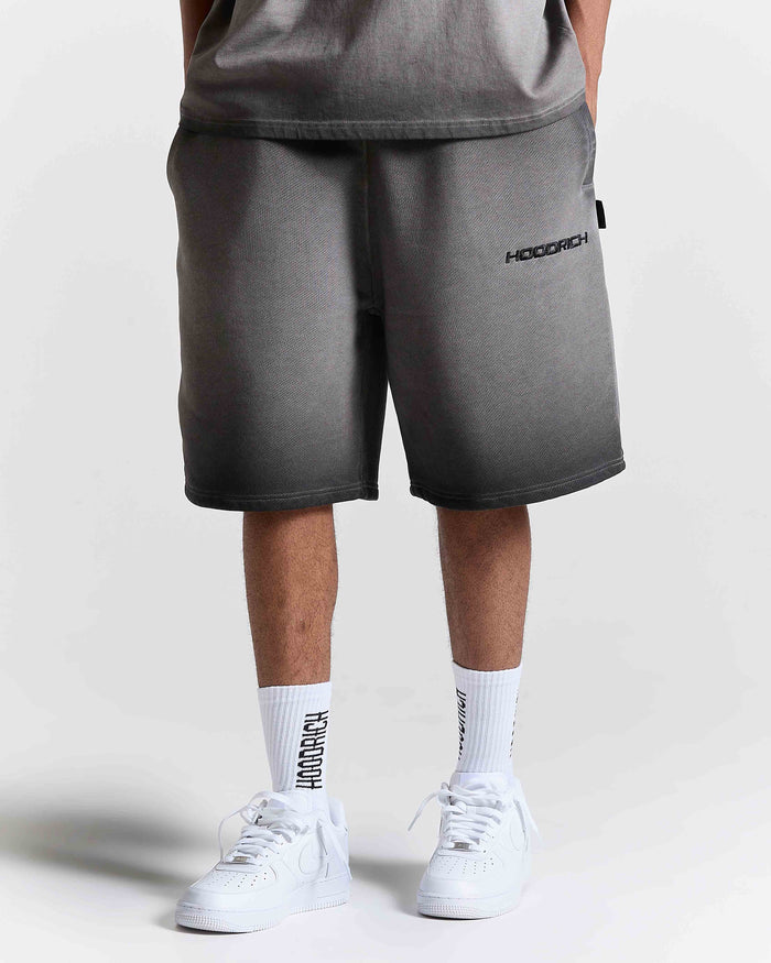 Model wearing oversized black oil wash shorts with Hoodrich logo embroidery, white socks, and white trainers.