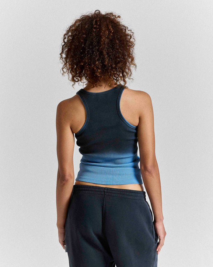Back view of a model wearing a black and blue ombre fitted racer vest.