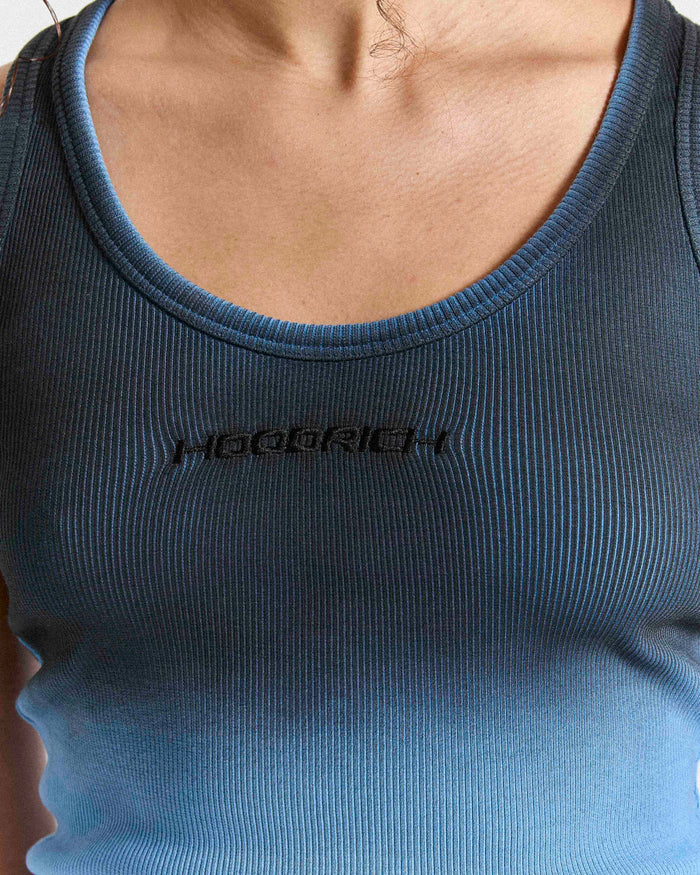 Close-up of the black embroidered Hoodrich logo on the chest of a blue and black ombre ribbed vest.