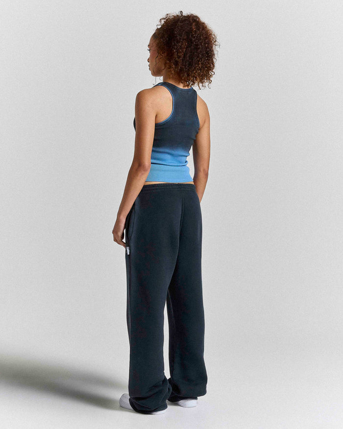 Back view of a model wearing a black and blue ombre fitted racer vest paired with black sweatpants.