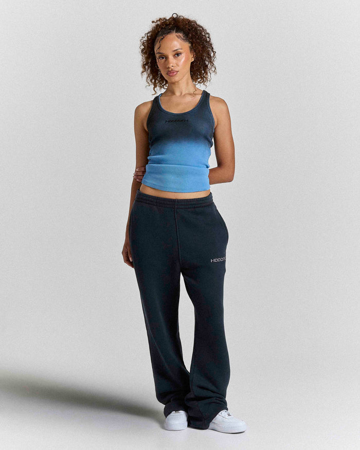 Model wearing a black and blue ombre fitted racer vest with black sweatpants.