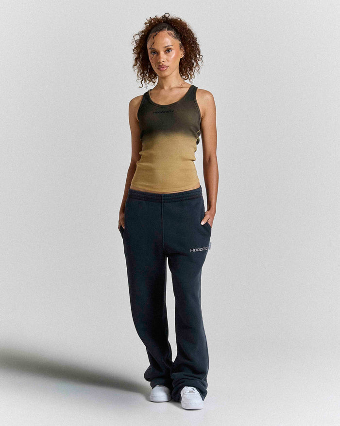 Woman wearing a gradient tank top and black pants on a plain background