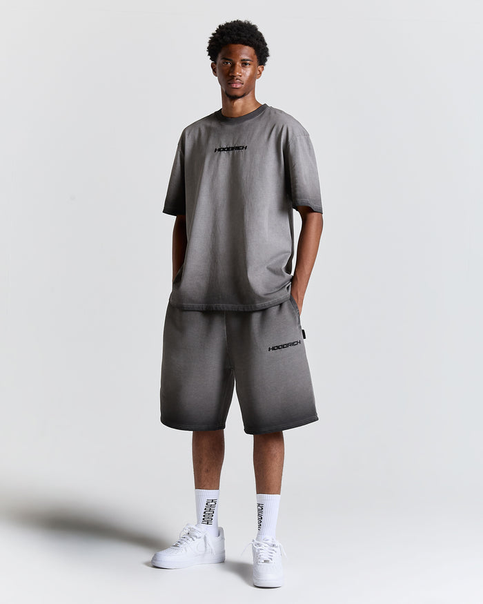 Male model wearing an oversized black oil wash t-shirt and matching shorts with a Hoodrich logo on the chest.