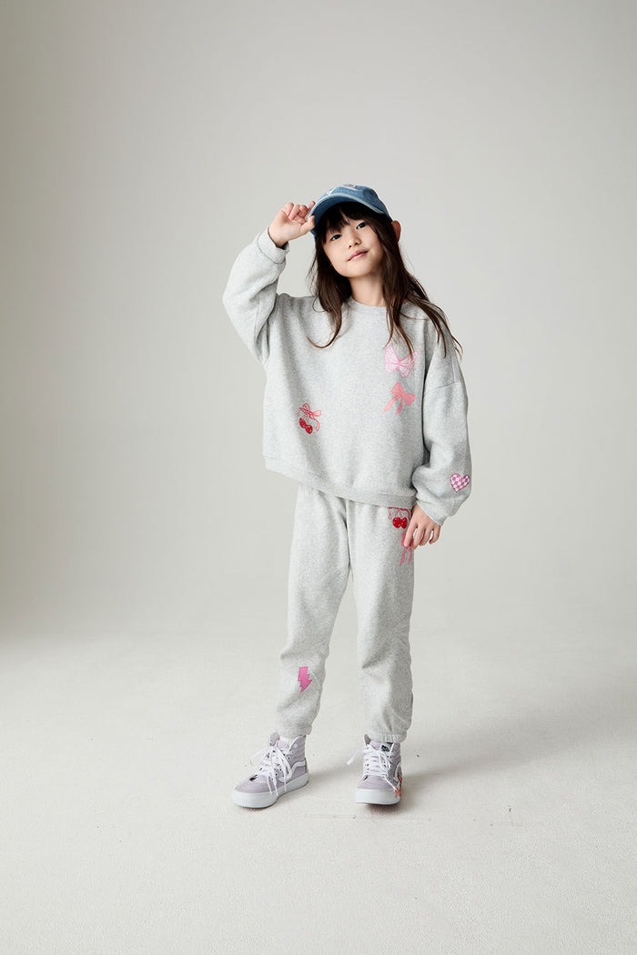 A full body front view of a girl wearing the Chaser irl Power Medley Girls Long Sleeve on a neutral background and blue hat