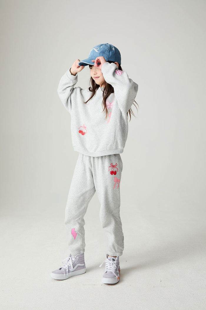 A full body front view of a girl wearing the Chaser irl Power Medley Girls Long Sleeve on a neutral background and hat