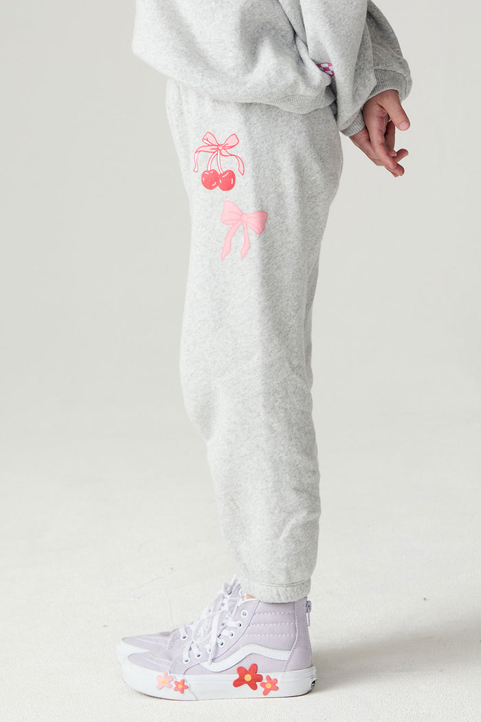 Side view of a girl wearing the Chaser Girl Power Medley Pants Girls Jogger on a neutral background with hands behind back