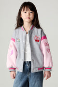 Front view of a girl wearing the Chaser Girl Power Medley Varsity Girls Varsity Jacket, white tee, and baggy jeans on a neutral background