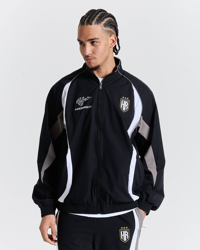 Person wearing a black and white tracksuit with visible branding on a plain background
