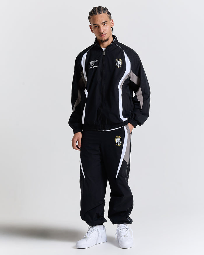 Person wearing a black tracksuit with white accents on a light gray background