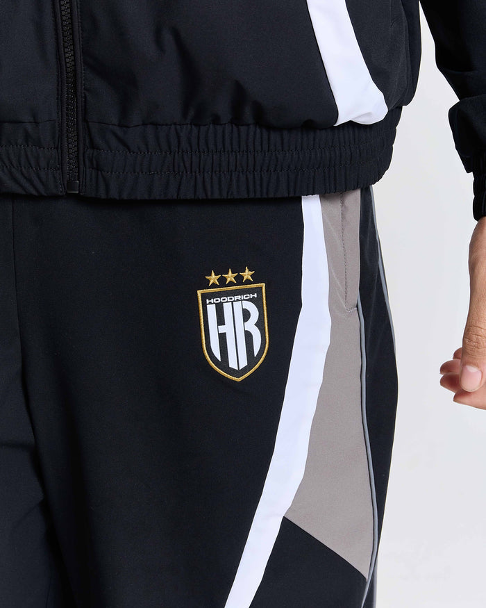 Black tracksuit with a logo on the leg against a light gray background
