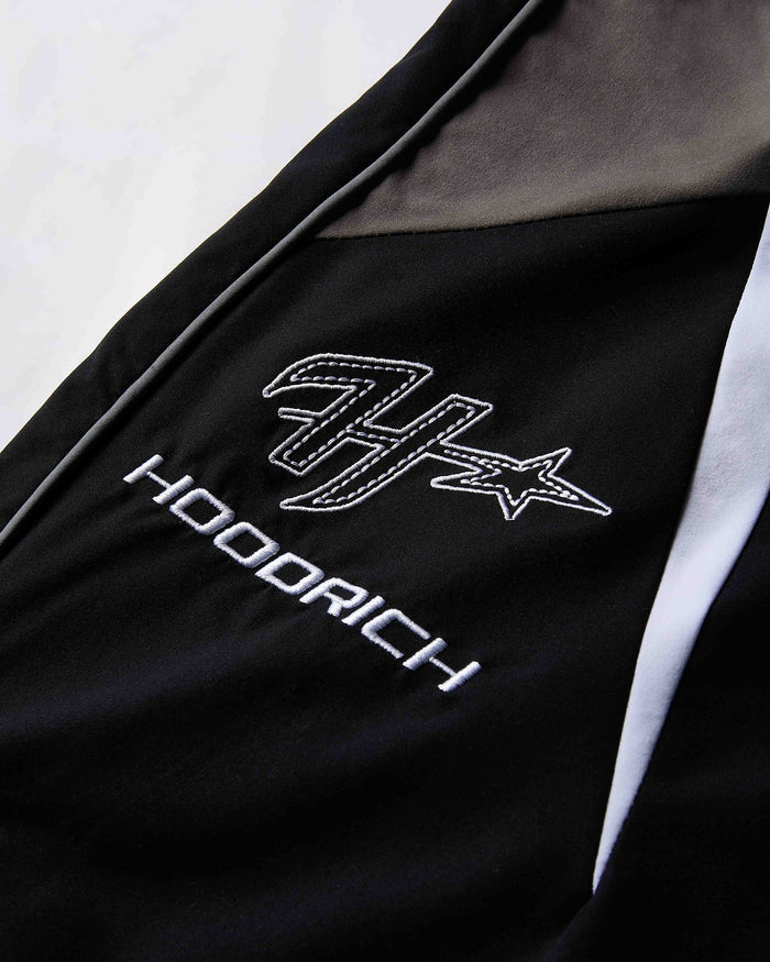 Black jacket with white embroidered logo and text on a light gray background