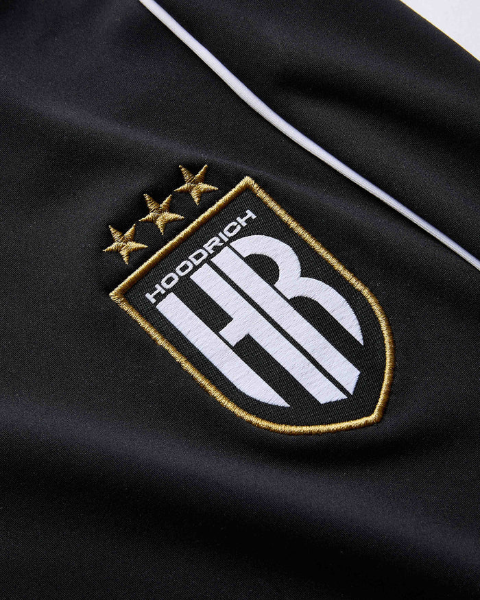 Close-up of a black fabric with an embroidered logo featuring 'Hoodrich HR' and three stars.