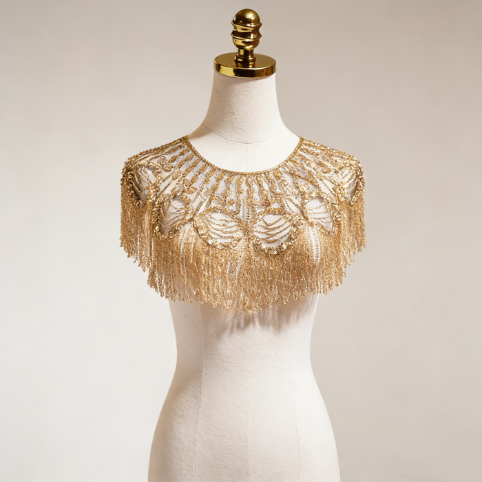 Gold beaded bridal capelet with hand embroidered sequins and flowing fringe on illusion mesh for luxury weddings.