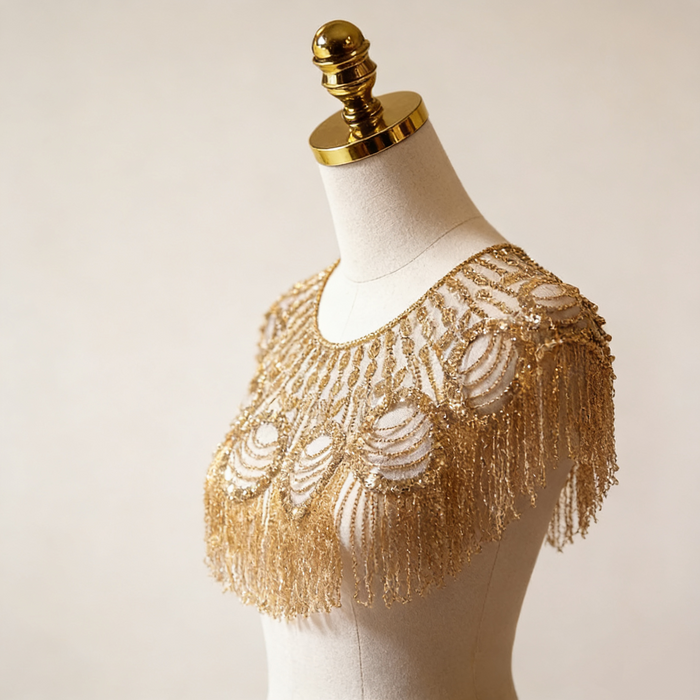 Gold beaded bridal capelet with hand embroidered sequins and flowing fringe on illusion mesh for luxury weddings.