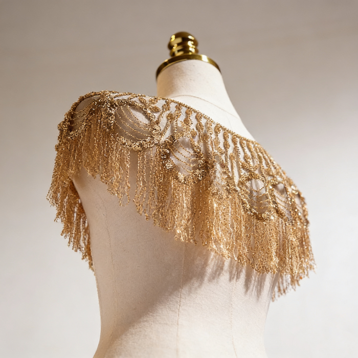 Gold beaded bridal capelet with hand embroidered sequins and flowing fringe on illusion mesh for luxury weddings.