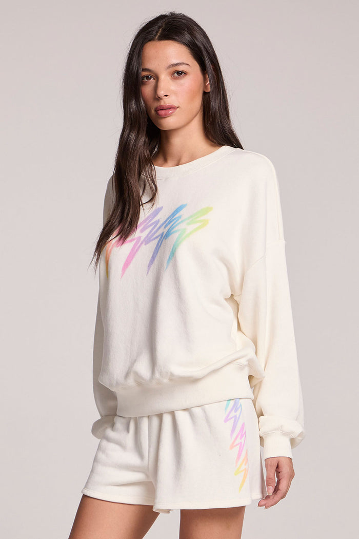 Side angle view of a woman wearing the Chaser Gradient Bolt Pullover and matching shorts on a neutral background