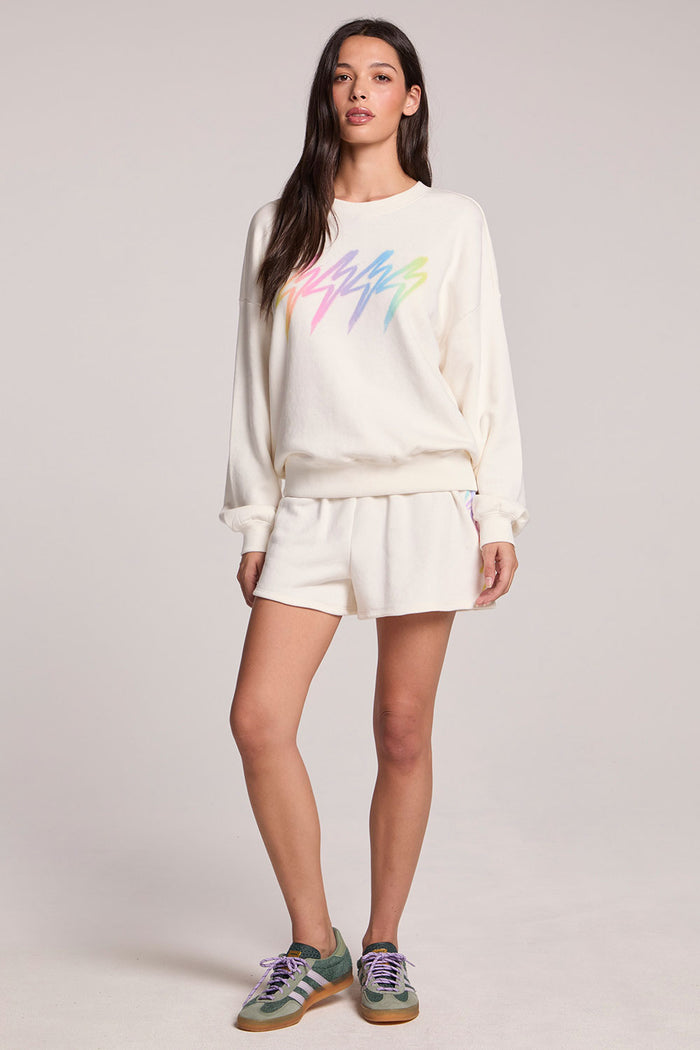 Front view of a woman wearing the Chaser Gradient Bolt Pullover and sneakers on a neutral background