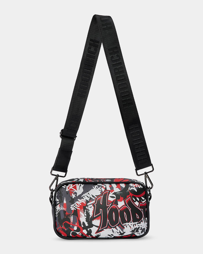 Crossbody bag with black strap and red and white graphic design on a light gray background