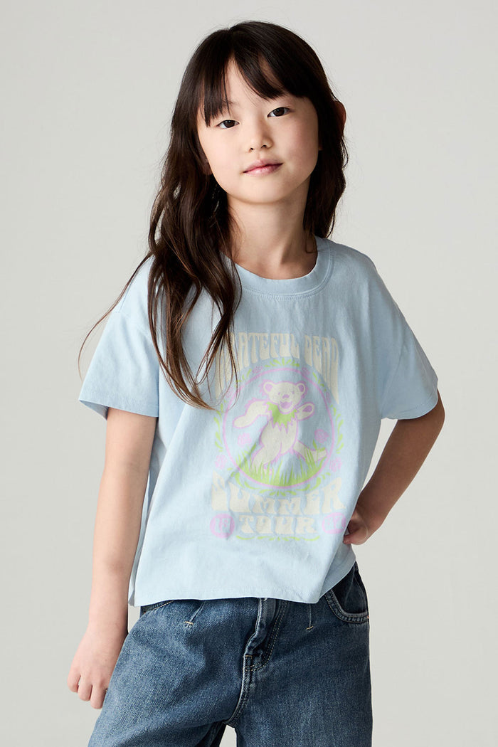 Front image of a girl wearing the Chaser Grateful Dead In The Park Girls Tee on a neutral background with jeans and one hand in pocket