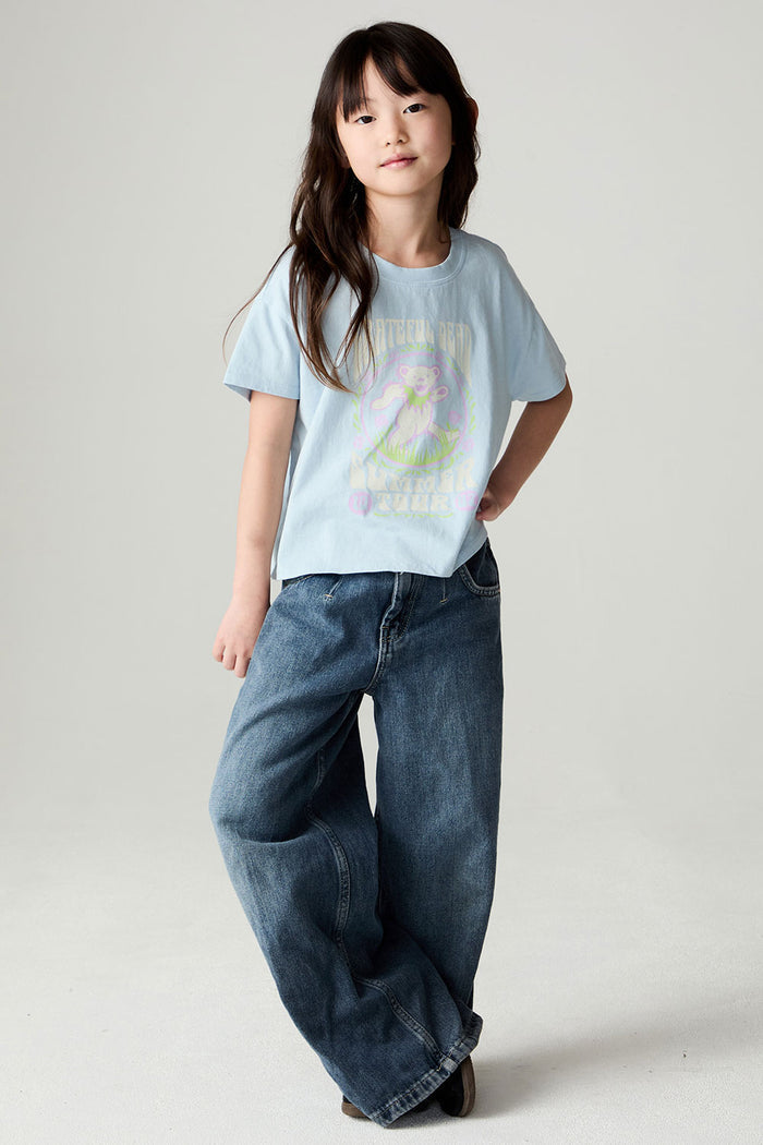 A full body front view of a girl wearing the Chaser Grateful Dead In The Park Girls Tee on a neutral background