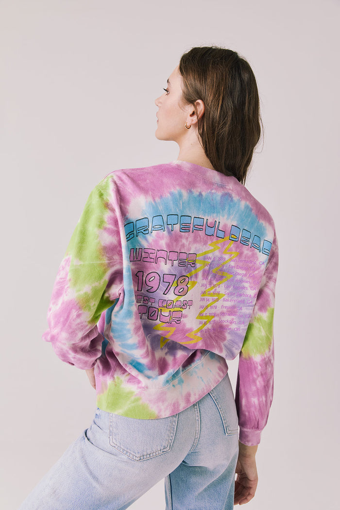Back view of woman wearing Chaser’s Grateful Dead Rose Logo Long Sleeve with “Grateful Dead Winter 1978 West Coast Tour” text in colorful block letters on a plain background