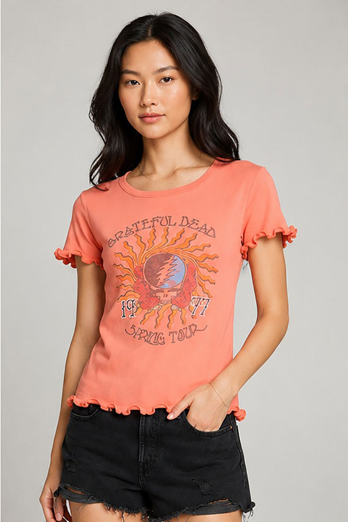 Women’s coral Grateful Dead 1977 Spring Tour graphic tee featuring lettuce-edge ruffle sleeves and hem, shown on model with black denim shorts