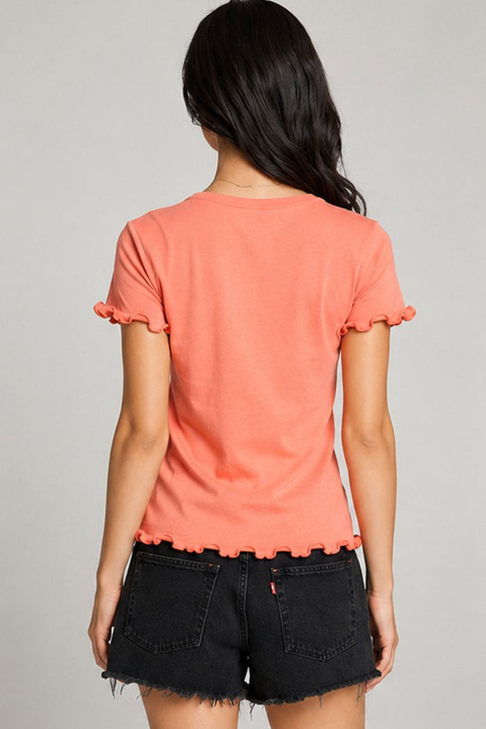 Back view of women’s coral Grateful Dead graphic tee with lettuce-edge ruffle sleeves and hem, styled with black denim shorts