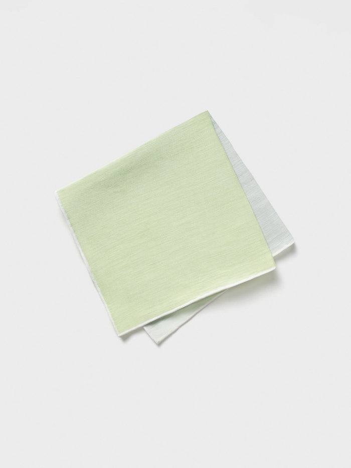Folded green and off-white pocket square on a white background.