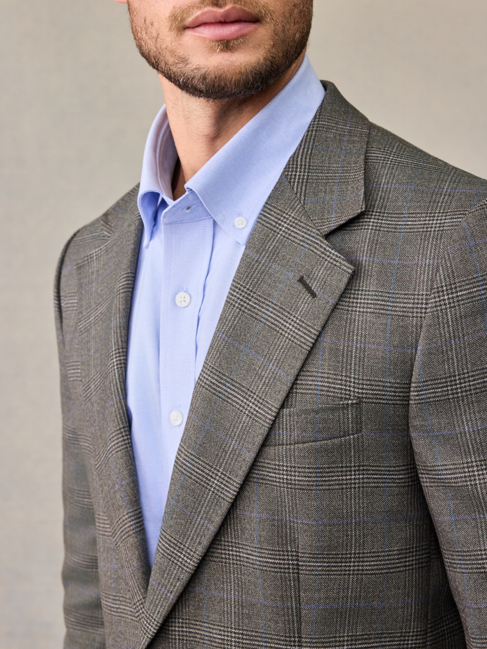 Close-up of a grey plaid sportcoat collar and lapel with light blue shirt.