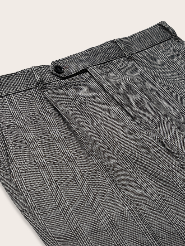 Close-up of grey plaid trouser waistband and pleat detail.