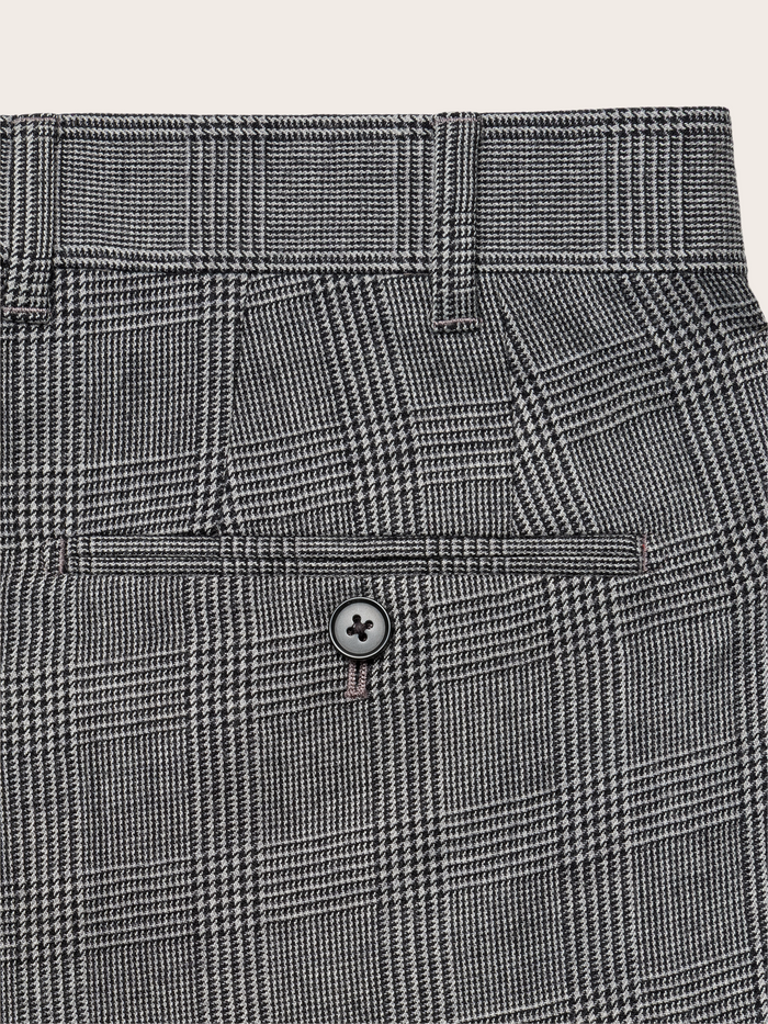Close-up of grey plaid trouser back pocket with button.
