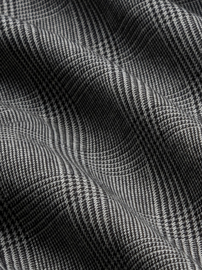 Close-up of grey plaid trouser fabric with folds.