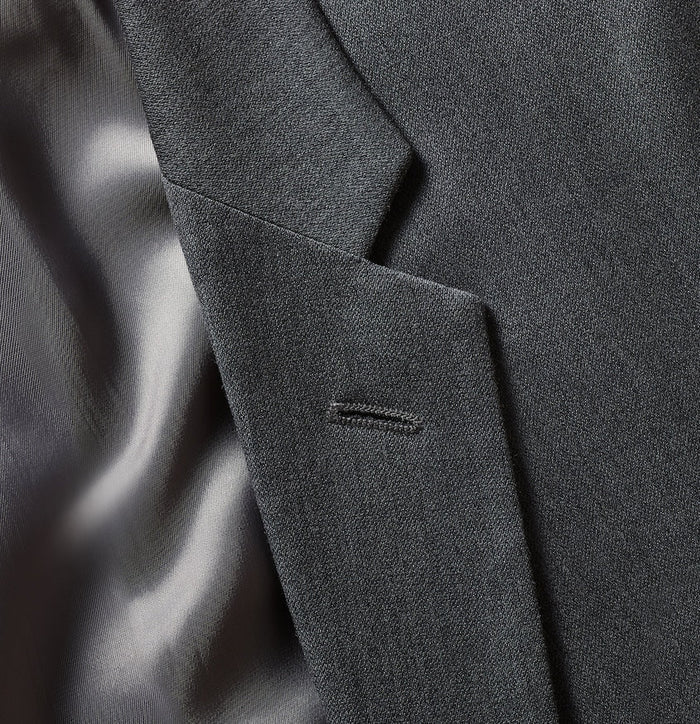 Close-up of grey suit lapel and welt pocket.