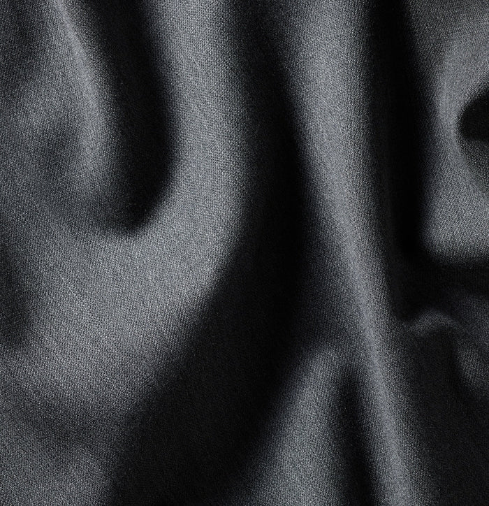 Close-up of dark grey suiting fabric with folds, showing woven texture