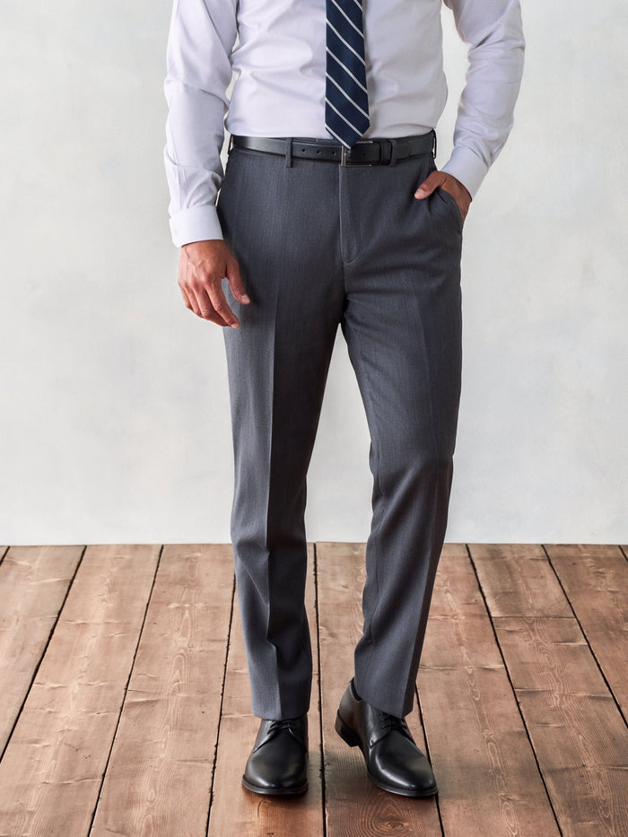 Cropped front view of grey suit trousers, black belt, and black shoes, tie hanging above