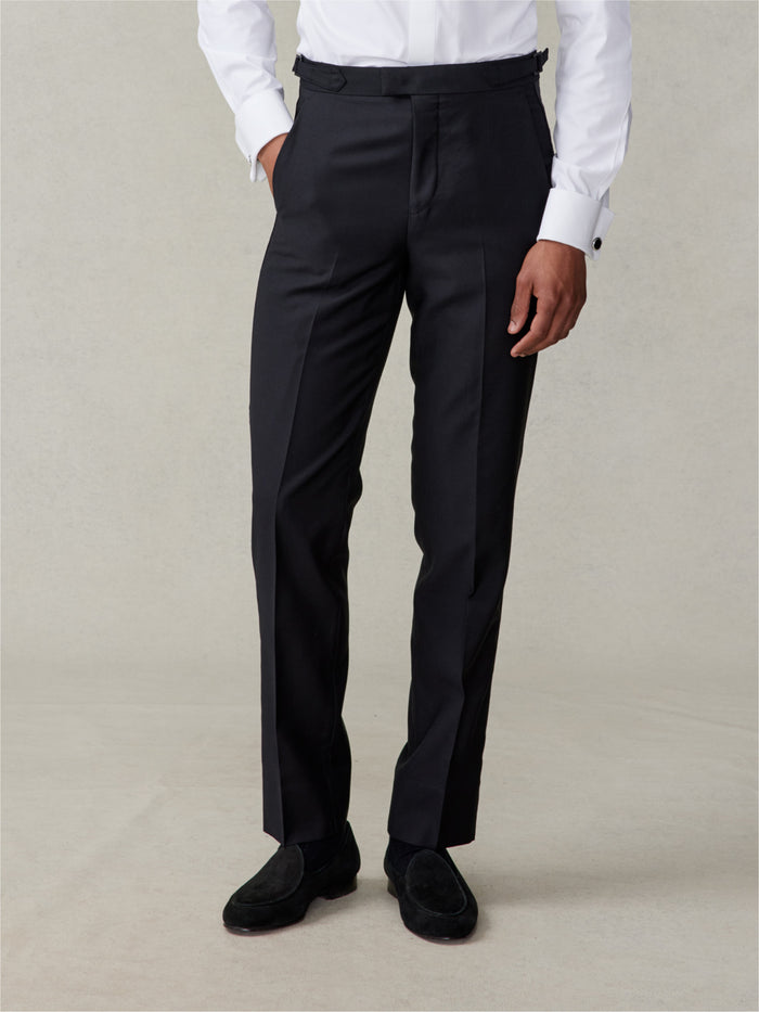 Cropped front view of black tuxedo trousers, slim fit, with white shirt above