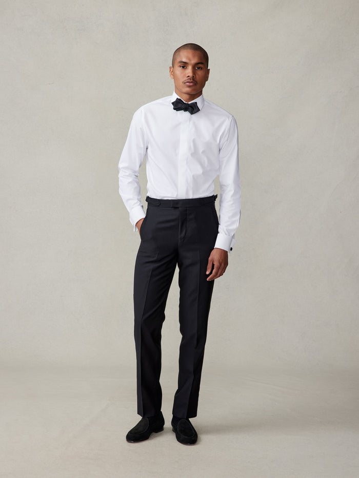 Man in white shirt and black bow tie with black tuxedo trousers, front view
