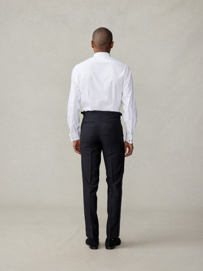 Back view of black tuxedo trousers with white dress shirt tucked in
