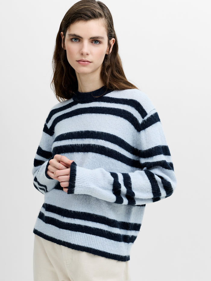 A woman wearing a blue striped relaxed fit jumper with long sleeves and a ribbed crew neckline.