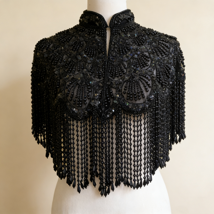Handmade black bridal capelet featuring intricate bead embroidery, shimmering sequins, and cascading beaded fringe.