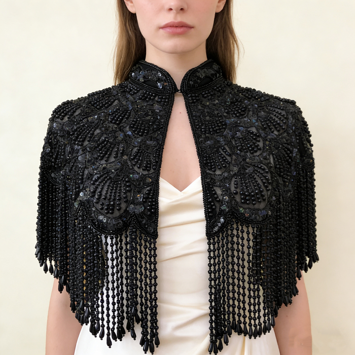Handmade black bridal capelet featuring intricate bead embroidery, shimmering sequins, and cascading beaded fringe.