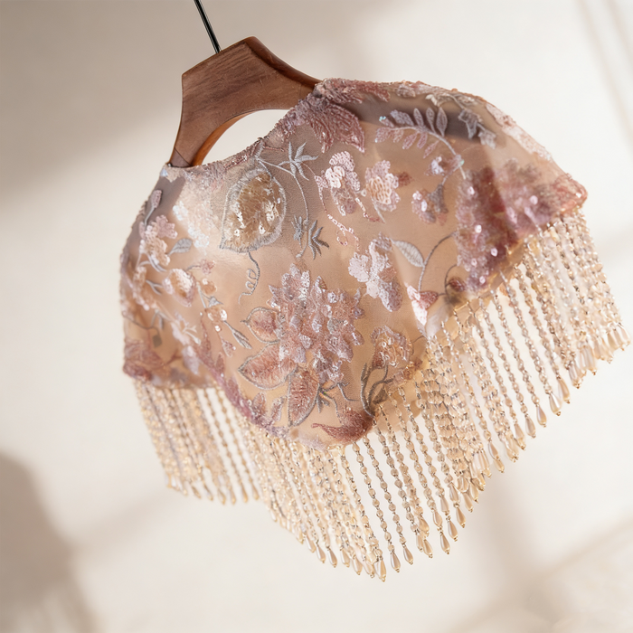 Handmade blush floral bridal cape featuring embroidered flowers, sequins, illusion tulle, and pearl-inspired fringe.