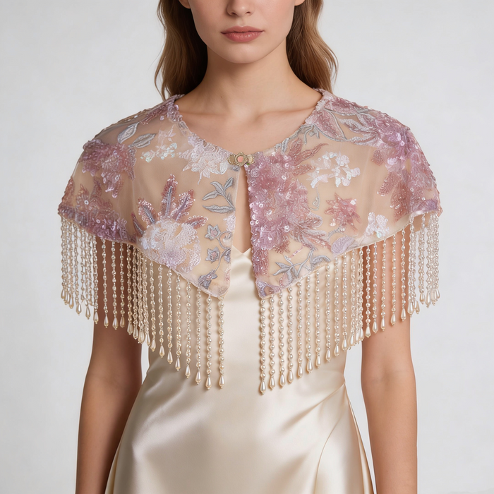Handmade blush floral bridal cape featuring embroidered flowers, sequins, illusion tulle, and pearl-inspired fringe.