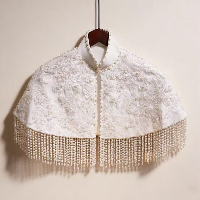 Handmade bridal cape featuring dimensional floral lace, hand-sewn bead embroidery, shimmering sequins, and elegant pearl-inspired fringe.