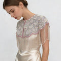 Handmade bridal cape featuring iridescent sequins, pearl bead embroidery, blush trim, and cascading pearl-inspired fringe.