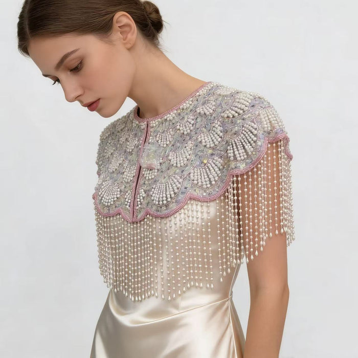 Handmade bridal cape featuring iridescent sequins, pearl bead embroidery, blush trim, and cascading pearl-inspired fringe.